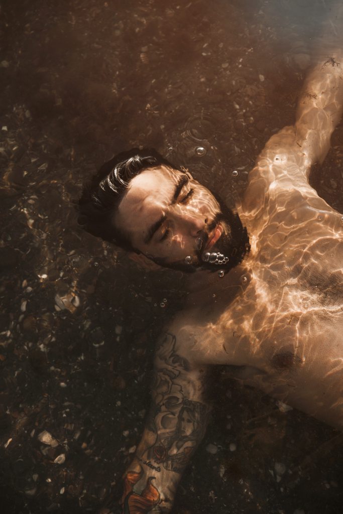 a man consciously swimming in water with eyes close trying to spiritually connect with water